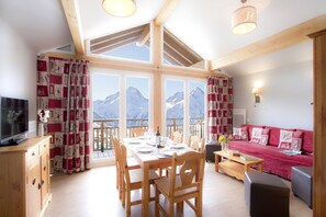 A cozy room with a dining table, chairs, a sofa, and a television. - Versatile Apartments in French Alps (Les Deux Alpes)