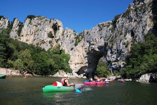 A group of people kayaking on a river with rocky cliffs in the background. - Holiday Home in Ardèche near Château de Ventadour (Pont-De-Labeaume)