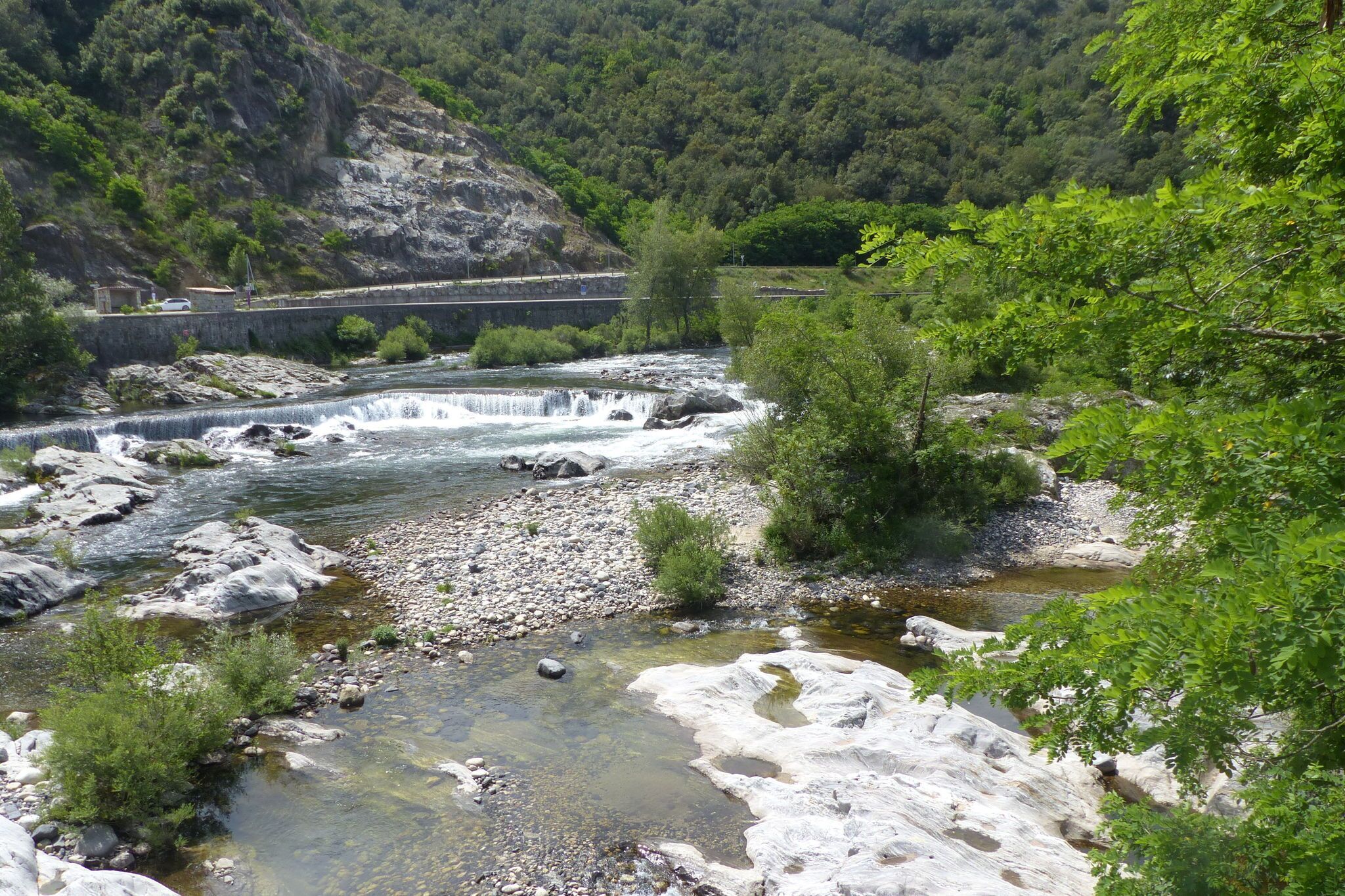 A river flowing through a rocky landscape with a bridge in the background.