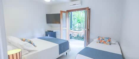 Quarto de hotel com duas camas, televisão, ventoinha no teto e porta de vidro deslizante para área externa.