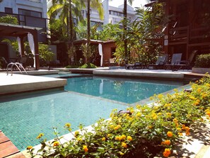Una piscina al aire libre, sillones reclinables de piscina