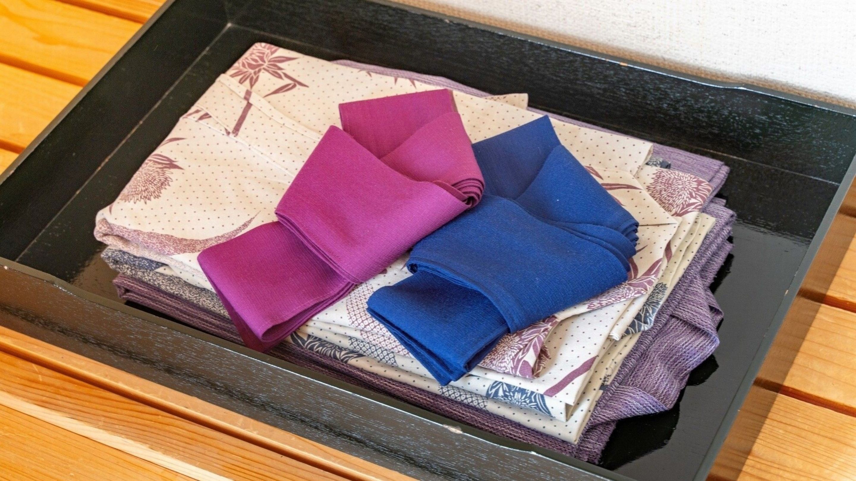 A black tray with folded towels in various colors and patterns.