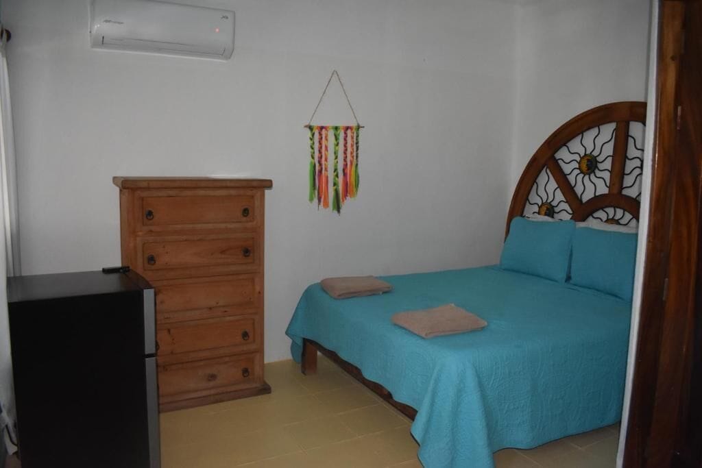 A bedroom with a bed, dresser, and an air conditioning unit.