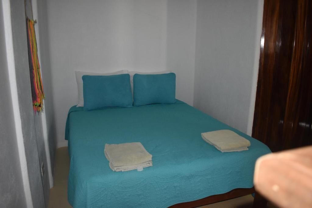 Ein kleiner, schlichter Raum mit einem Bett, zwei Kissen und zwei gefalteten Handtüchern.
