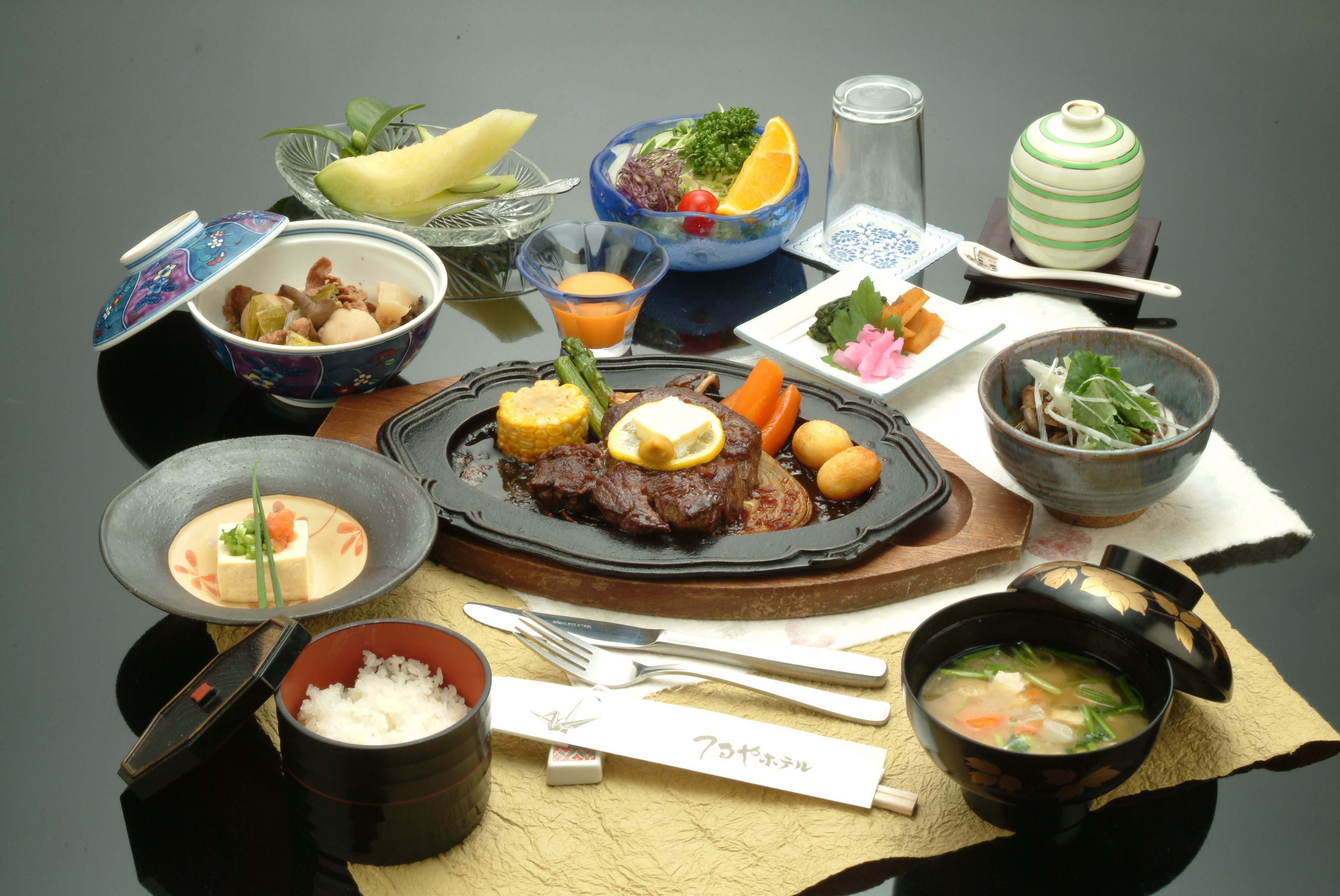 A variety of dishes including a bowl of soup, a plate of meat, and several side dishes.
