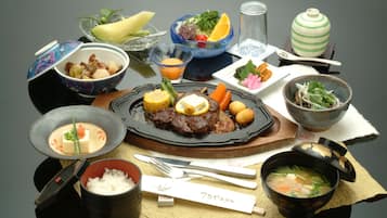 A variety of dishes including a bowl of soup, a plate of meat, and several side dishes.