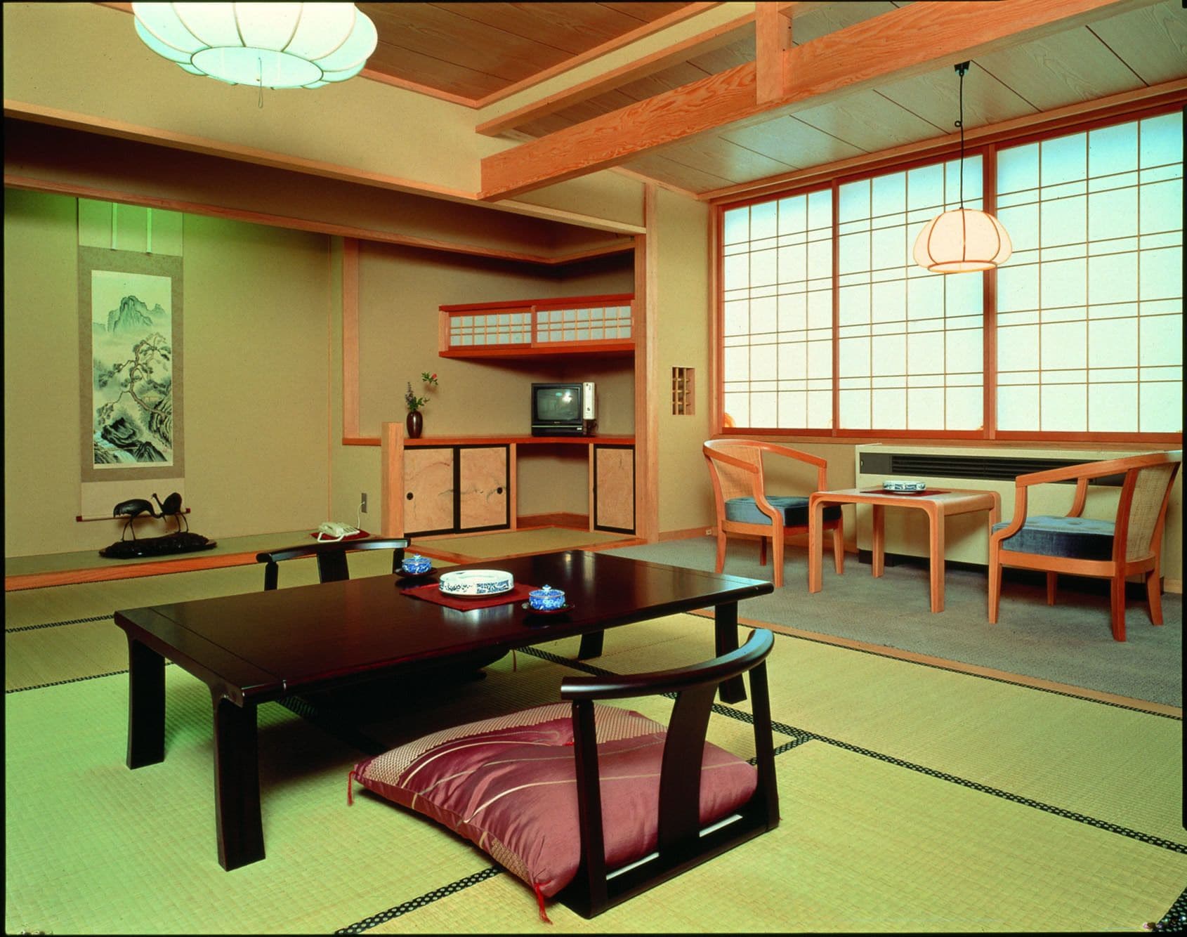 A traditional Japanese-style room with tatami flooring, a low table with cushions, and sliding shoji doors.