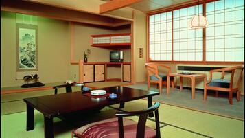 Una habitación japonesa tradicional con suelo de tatami, una mesa baja con cojines y puertas correderas shoji.
