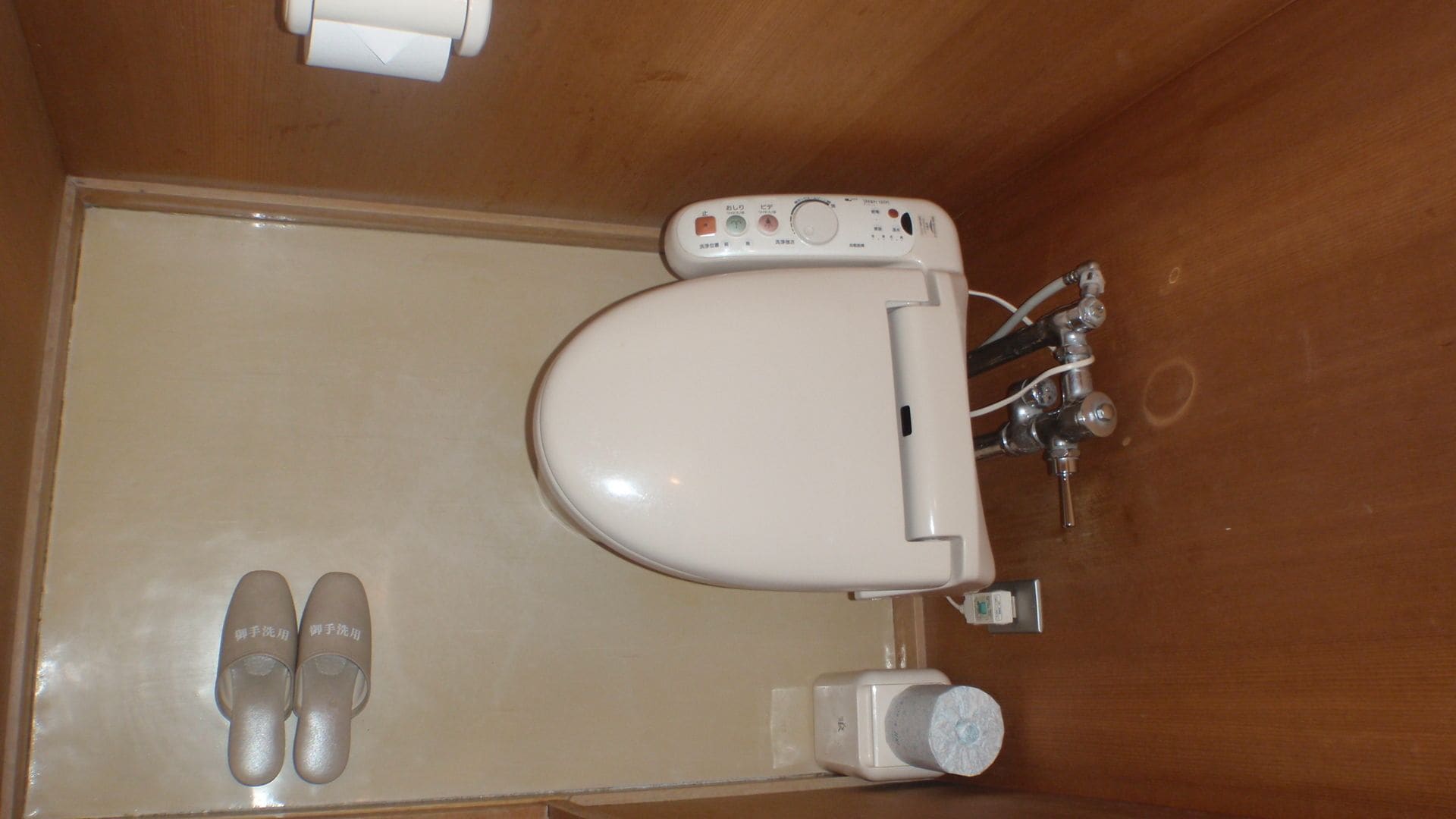 Des toilettes dotées d’un panneau de commande, d’un repose-pieds et d’un porte-rouleau de papier toilette.