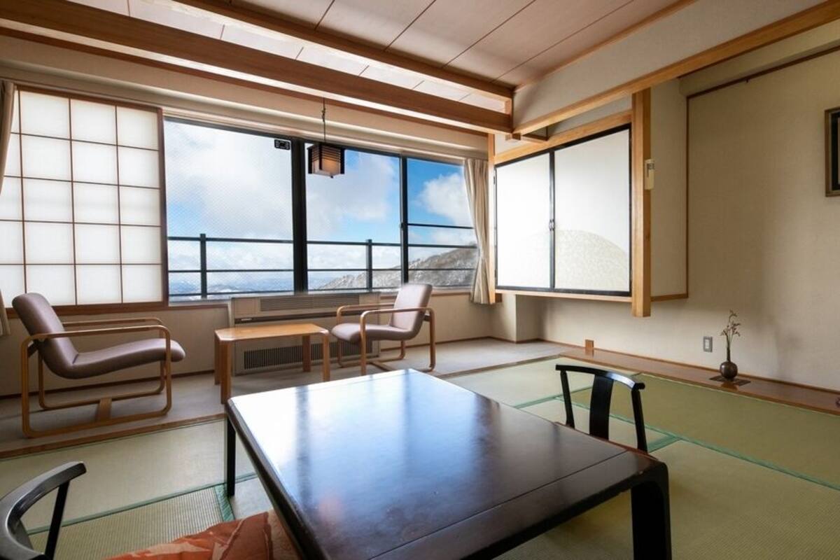 Una habitación japonesa tradicional con suelo de tatami, una mesa baja y sillas.