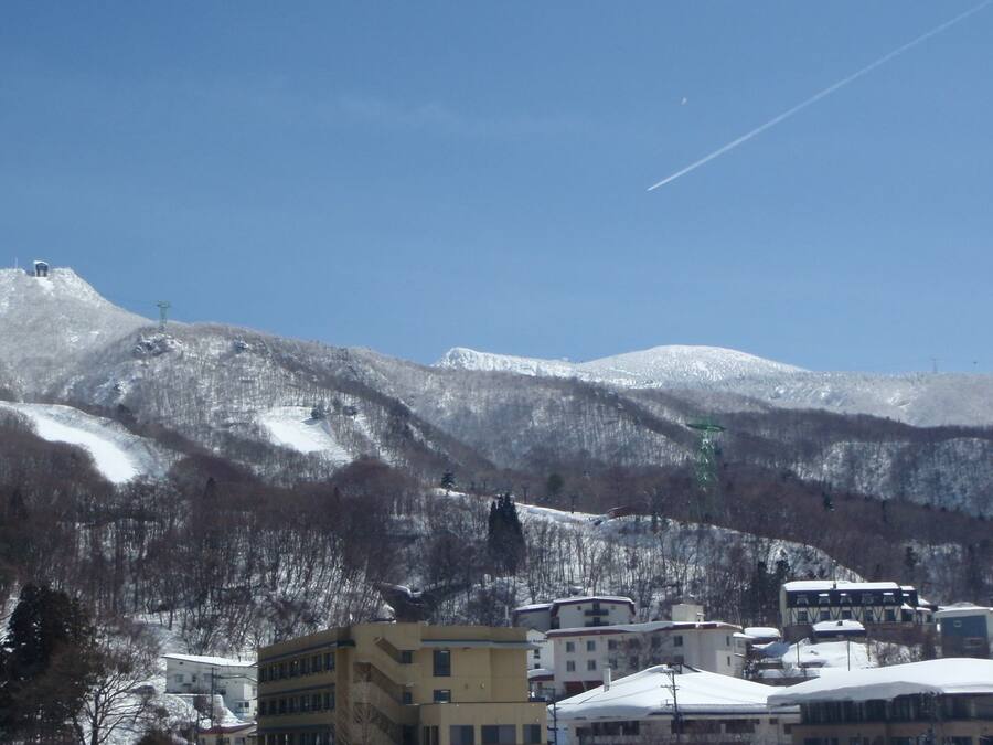 A mountain town with buildings in the foreground and snow-covered mountains in the background.