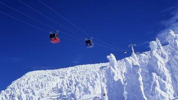 A ski lift with cabins moving over a snowy mountain slope.