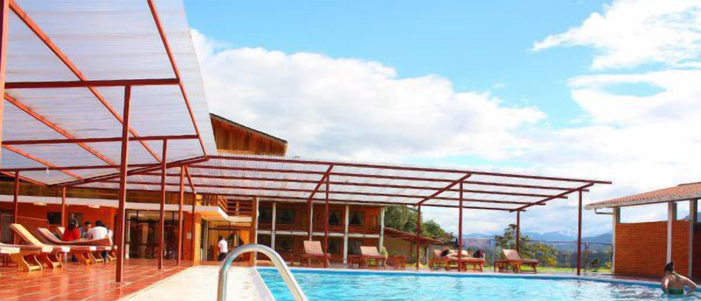 Zona de piscina con sillones de descanso, un área de estar cubierta y vistas a las montañas.