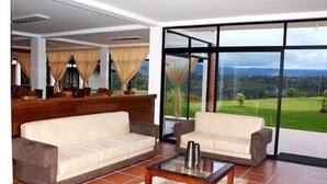 A spacious living area with a large window offering a view of a green landscape. There are two sofas and a coffee table. - Hosteria Farallon (Sevilla Don Bosco)