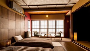 A modern hotel room with a large bed, two chairs, a small table, and a large window with a view. - Hotel Yamakawa (Yonezawa)