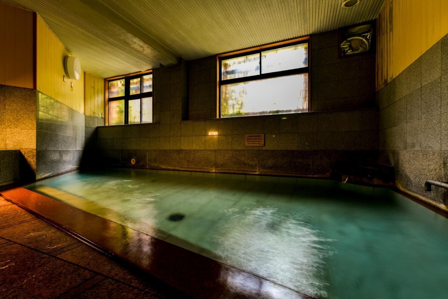 A public swimming pool with tiled walls and windows.