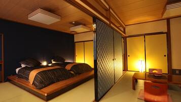 A traditional Japanese-style bedroom with tatami flooring, a low wooden bed, and sliding shoji screens.