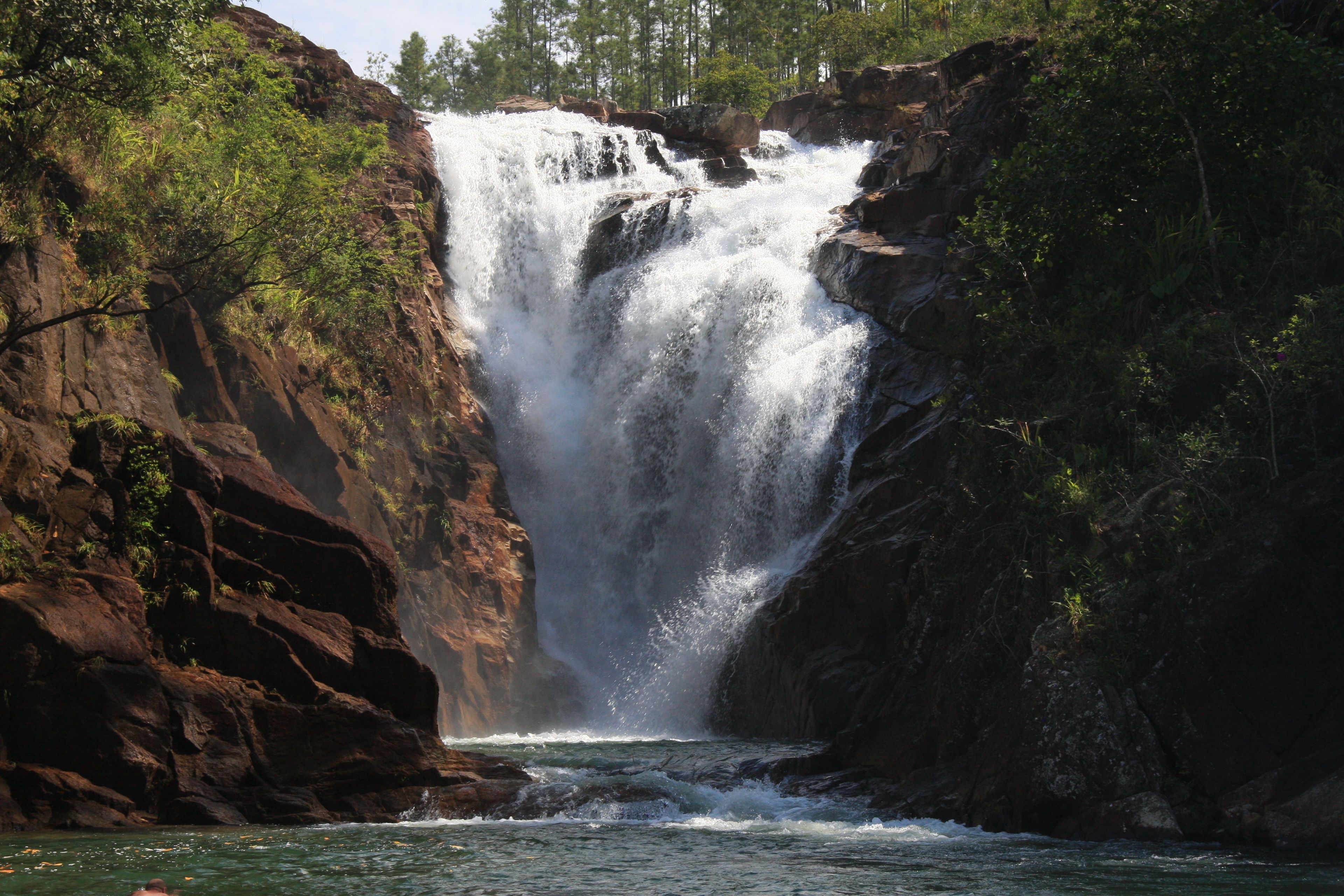 Une cascade se déversant le long d’une falaise rocheuse, entourée d’une végétation luxuriante.