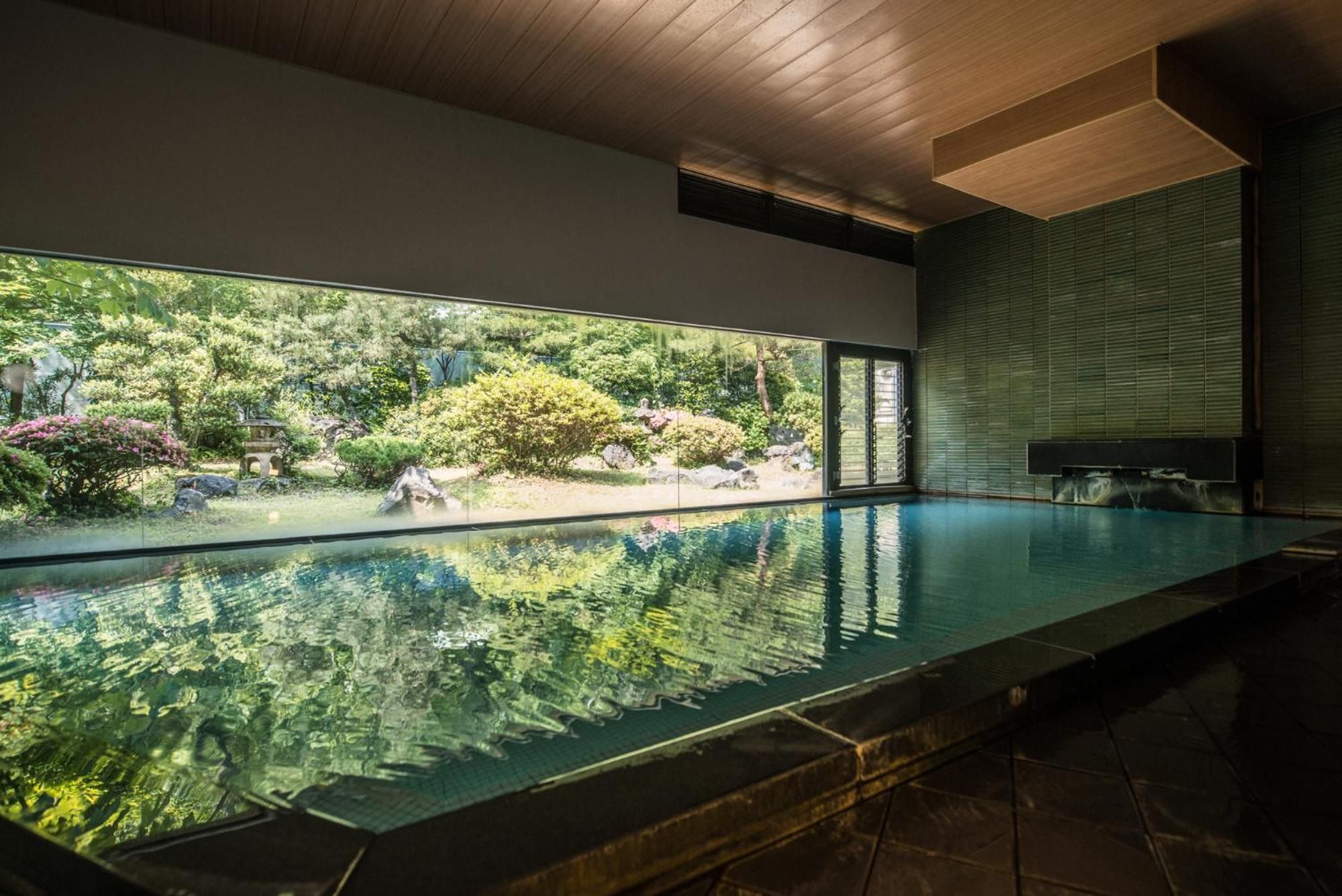 An indoor swimming pool with a view of a landscaped garden.