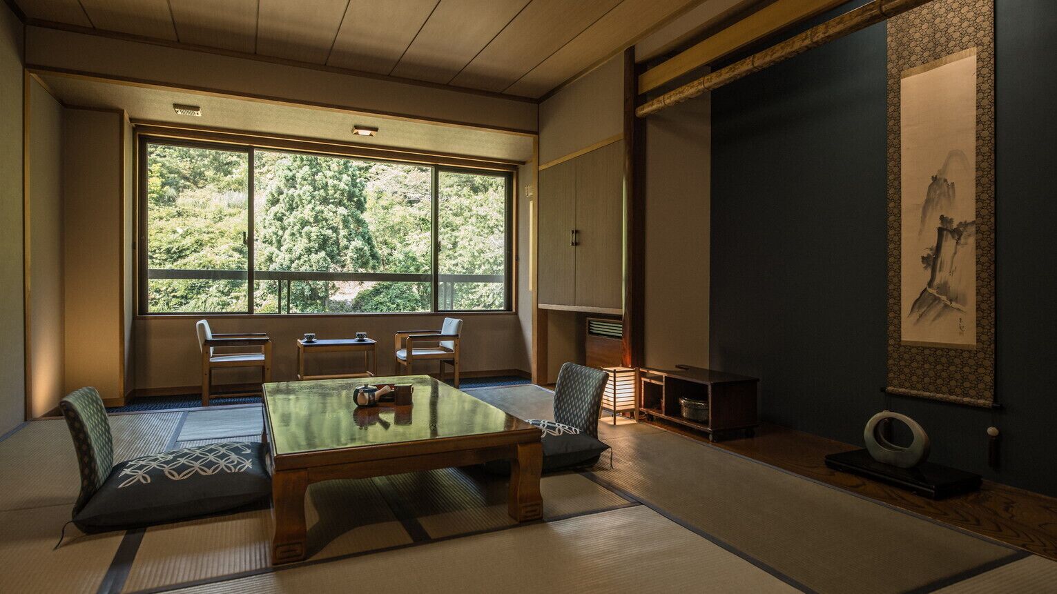 A traditional Japanese room with tatami flooring, a low table, and a large window.
