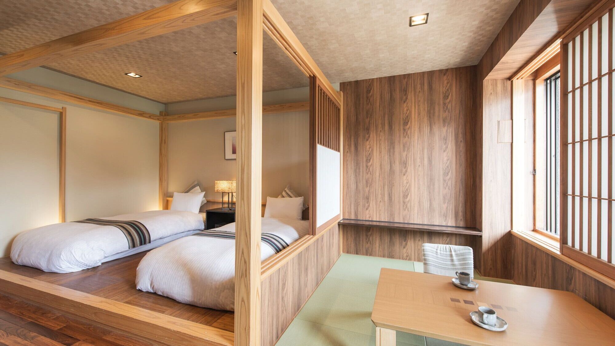 A traditional Japanese-style room with a tatami mat floor, a low table with a cup, and a bed with a wooden headboard.