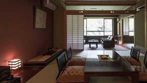 Perinteinen japanilaistyylinen huone, jossa on tatamimatto, matala pöytä ja istuimia.