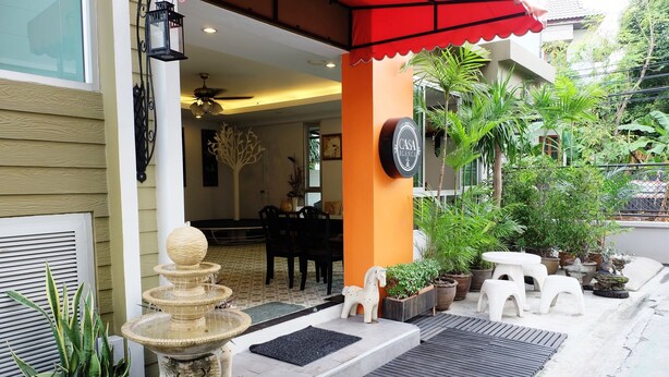 A hotel entrance with a stone fountain, outdoor seating, and potted plants. - Casa Blanca (Bangkok)