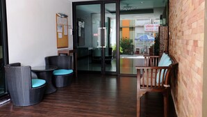 A modern indoor space with a glass door leading to an outdoor area, wicker furniture, and a wooden bench. - Casa Blanca (Bangkok)