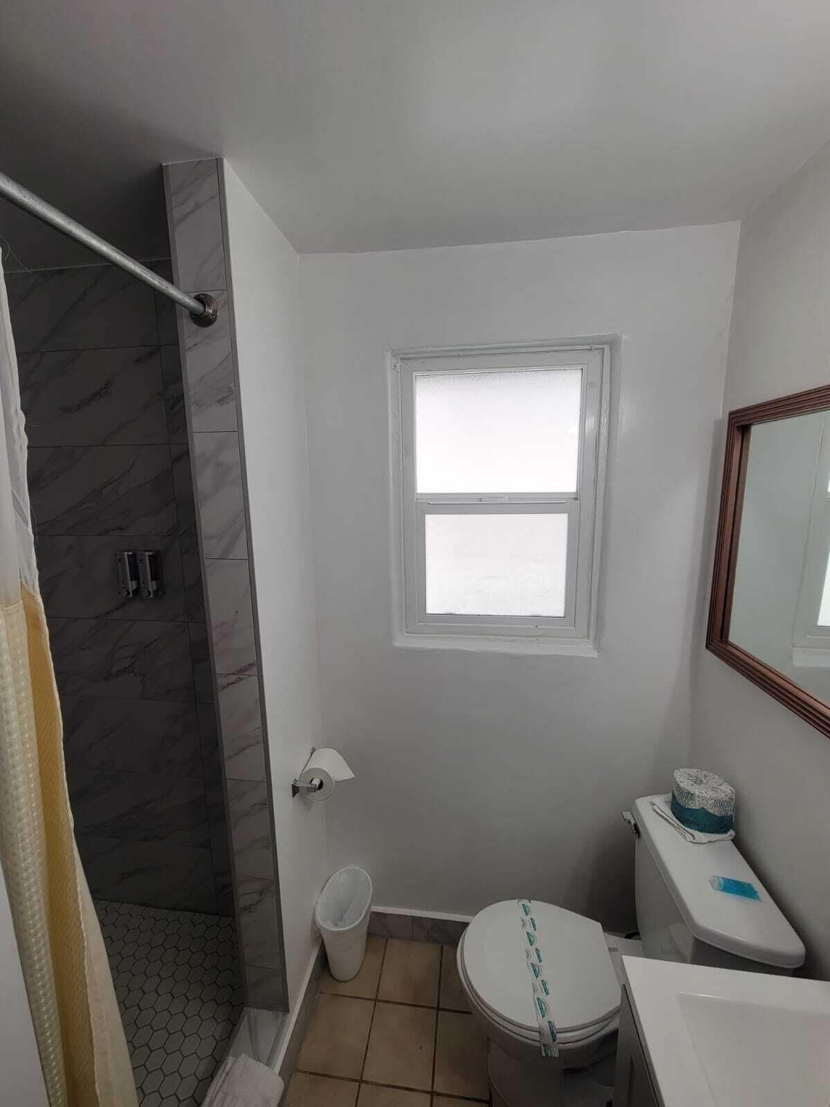 Une salle de bain avec une douche, des toilettes, un lavabo et une fenêtre.