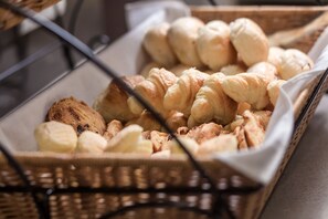 A basket of assorted baked goods including croissants and muffins.