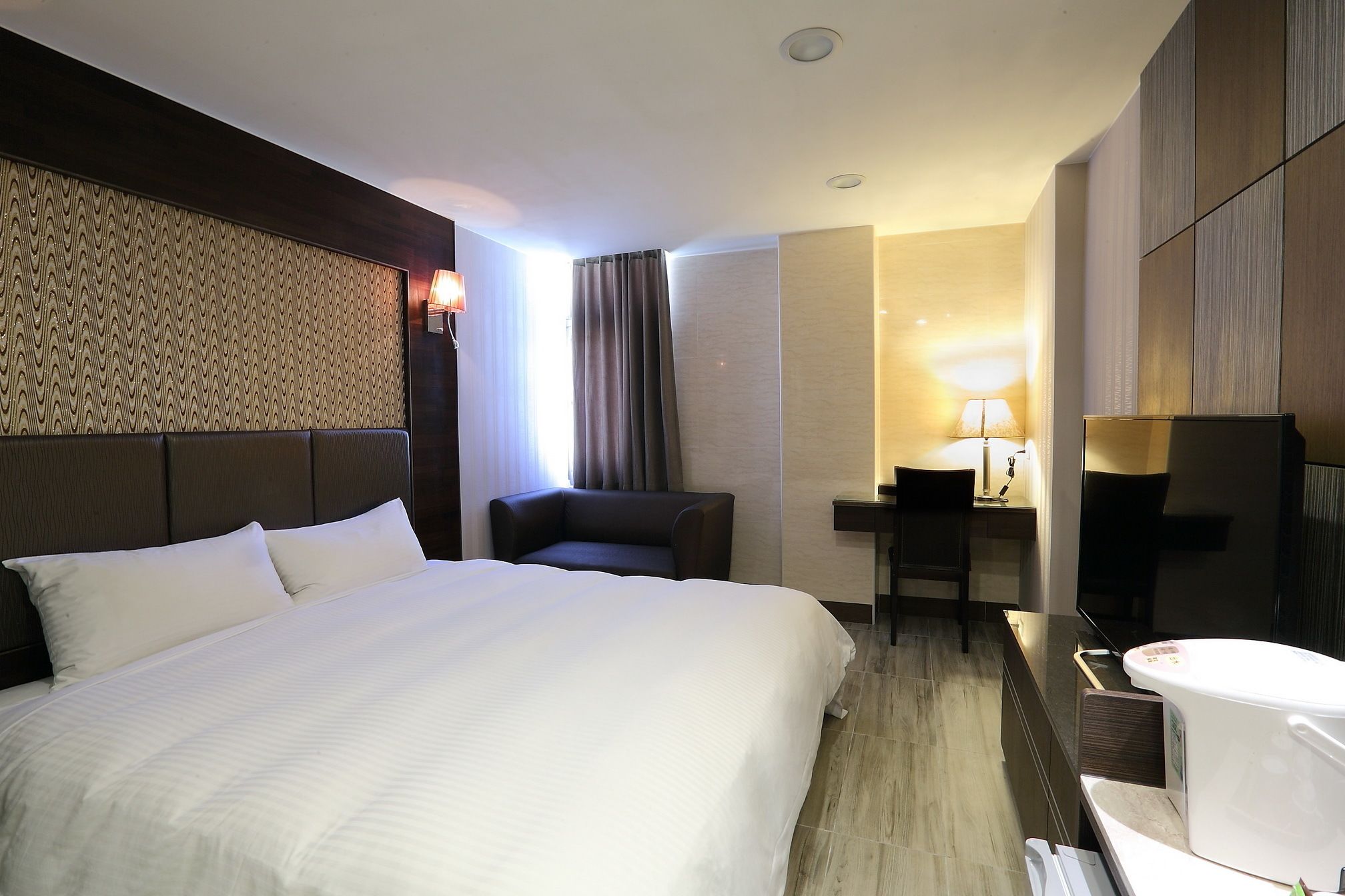 Una habitación de hotel con una cama grande, un escritorio, una silla, un televisor y un baño.