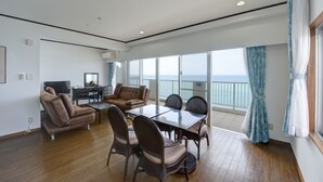 Amplia habitación con una gran mesa de comedor, asientos cómodos, televisión y vista al mar.