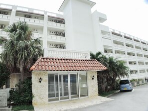 Un hôtel à la façade blanche, doté d’un toit recouvert de tuiles rouges et d’une petite entrée avec des portes vitrées.