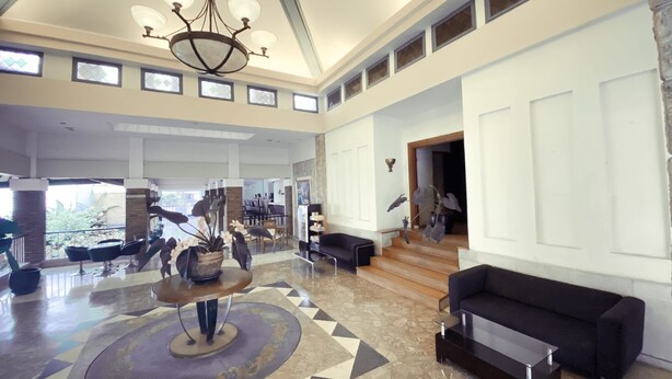 A spacious lobby with a chandelier, a coffee table, and a sofa. There are multiple windows and a view of the outdoors. - De Ningrat Topas Galeria (Bandung)
