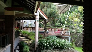 A restaurant with outdoor seating, a brick wall, and a sign indicating a drug store. - De Ningrat Topas Galeria (Bandung)