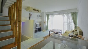 Una sala de estar moderna con una escalera, un televisor y un comedor.