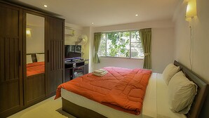 Un dormitorio con cama, escritorio, armario y ventana con cortinas.
