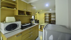 Una cocina compacta con armarios de madera, microondas, cafetera y refrigerador.
