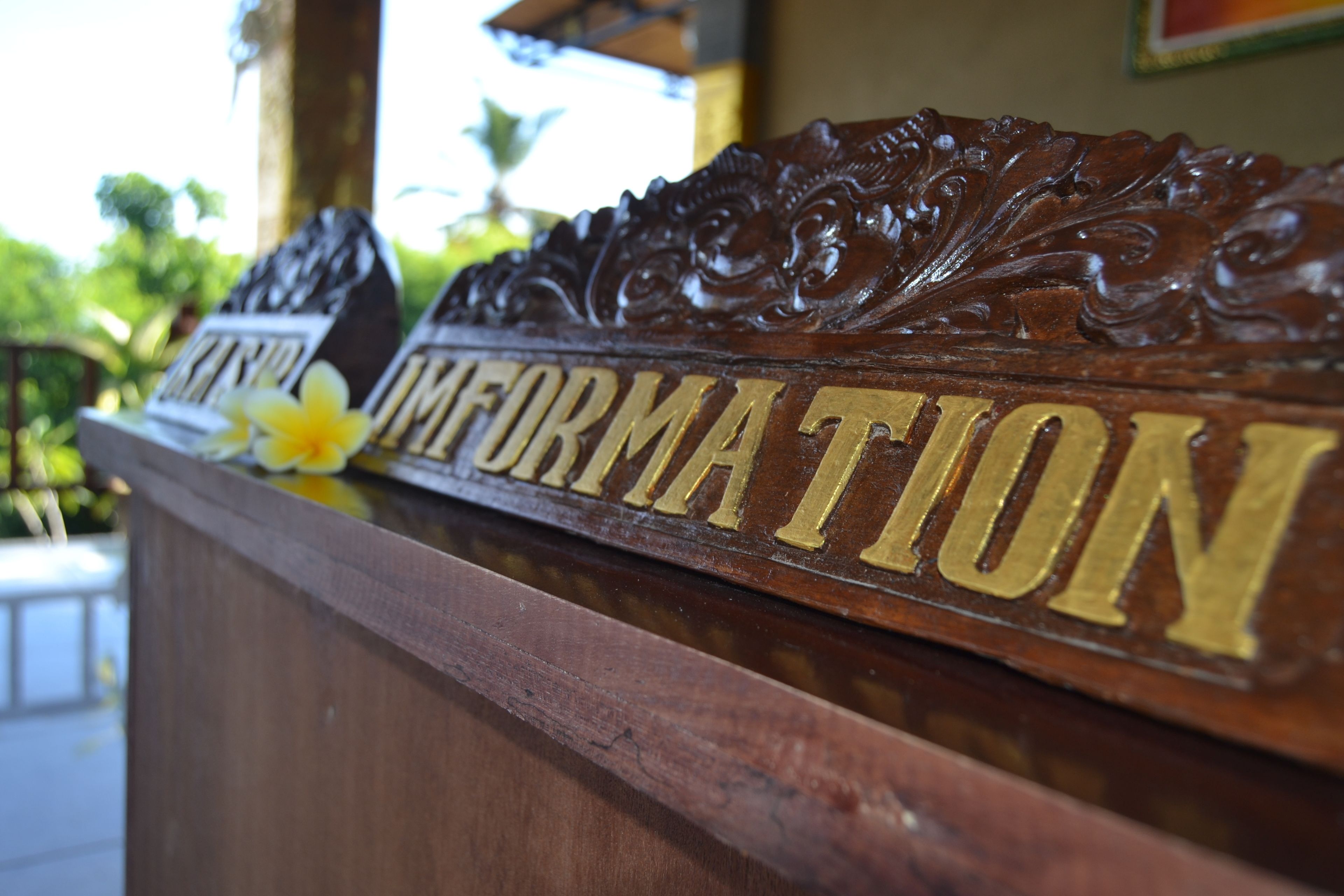 A wooden reception desk with carved details and the words "Information" prominently displayed.
