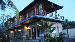 A two-story building with a balcony, a pool, and tropical landscaping. - Menjangan Sari (Pejarakan)
