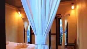 A hotel room with a bed, curtains, a chair, and a window with curtains. - Menjangan Sari (Pejarakan)