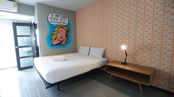 A modern hotel room with a bed, a nightstand, and a wall mural.