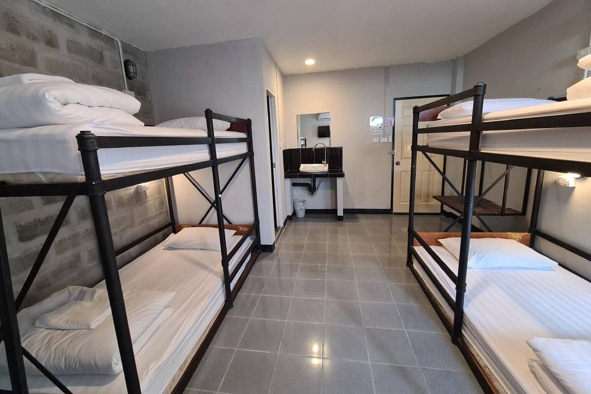 Une chambre de dortoir avec des lits superposés, une petite kitchenette et un miroir.