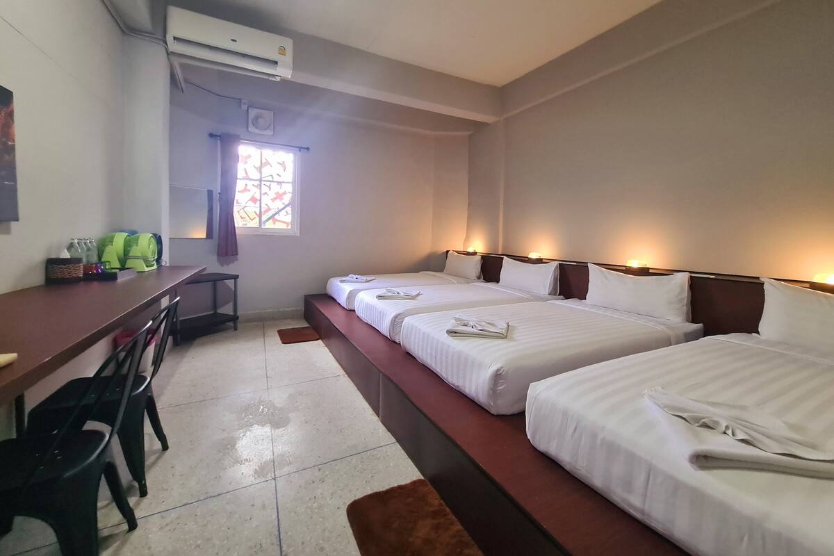 Une chambre d’hôtel avec deux lits, un bureau, des chaises et un appareil de climatisation.