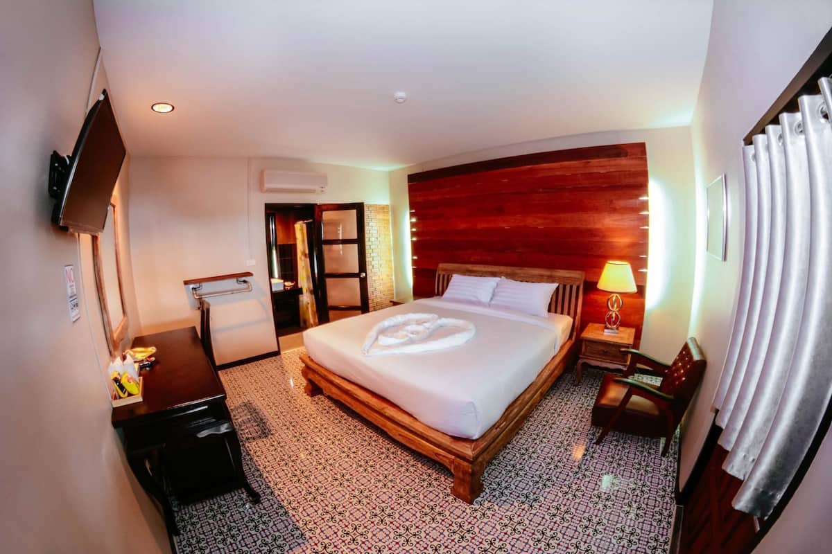 Une chambre d’hôtel avec un lit, un bureau, une chaise, une télévision et une porte de salle de bain.