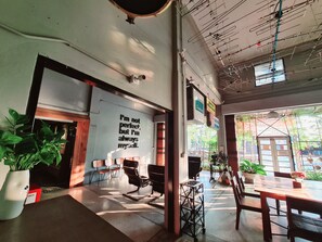 A modern interior with a motivational quote on the wall, a seating area with chairs and tables, and a view of the street outside. - The 8 Factory Hotel Phitsanulok (Phitsanulok)
