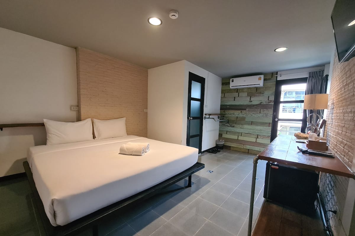 Une chambre d’hôtel équipée d’un lit, d’un bureau, d’une chaise, d’une fenêtre et d’un appareil de climatisation.