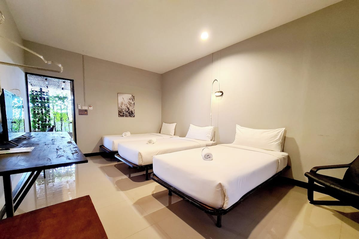 Une chambre d’hôtel avec deux lits, un bureau avec un ordinateur et une vue sur la verdure.