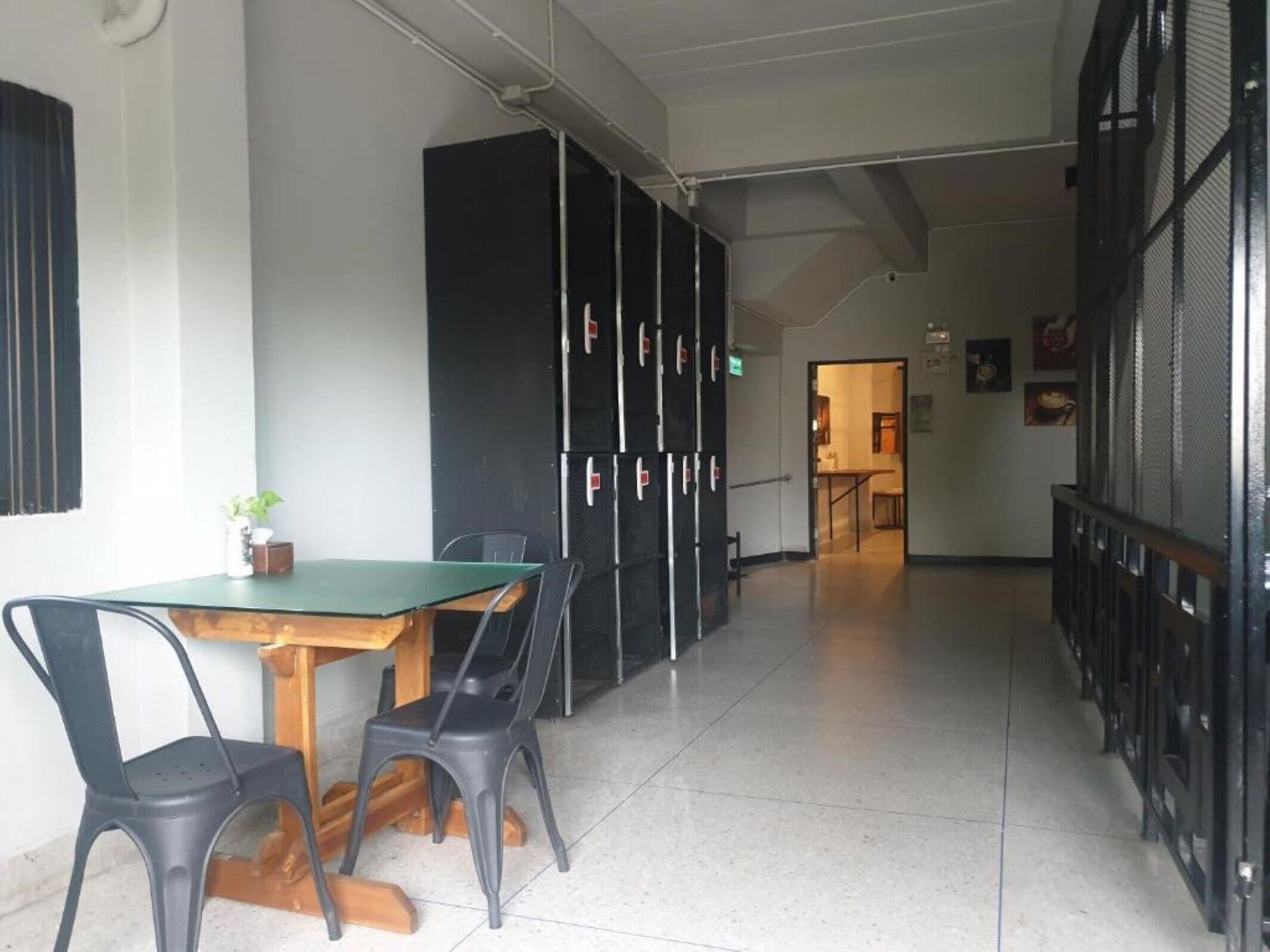 A meeting room with a table and chairs, a black storage unit, and a corridor leading to a kitchen area.