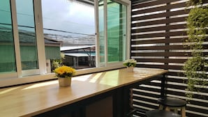 Eine Holztresorecke mit einem großen Fenster, zwei Barhocker und einem Blumentopf.
